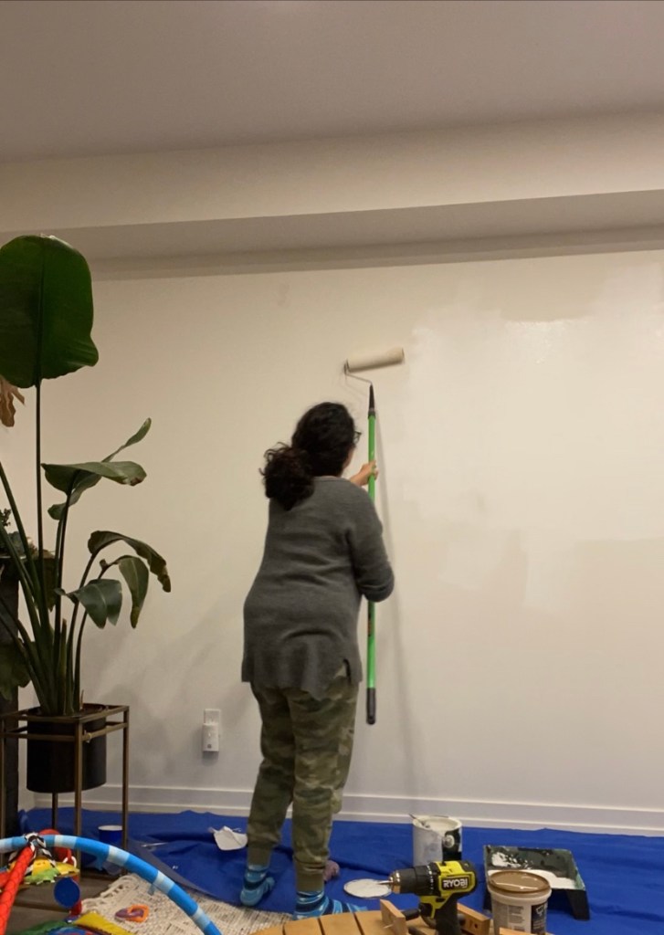 A woman painting the wall to prepare for a living room accent wall
